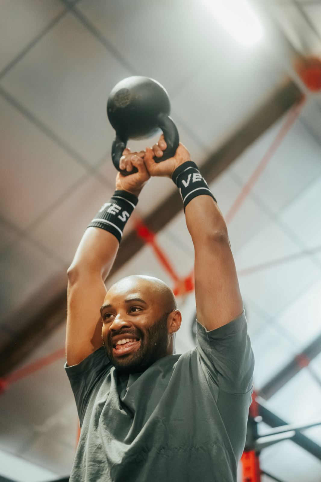 Un membre sourit, kettlebell au-dessus de la tête
